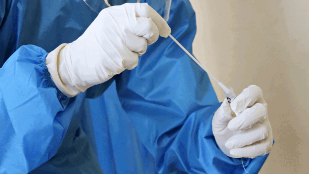 Close up of lab assistant with swab and tube in hands