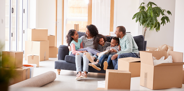 family sitting on sofa with boxes from moving house