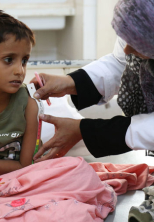 Small child sat on bed having a medical review