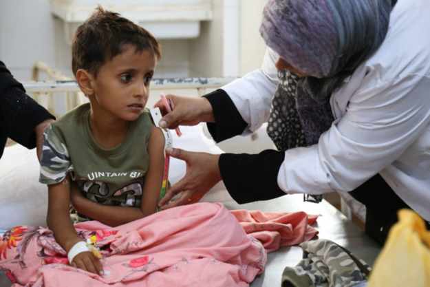 Small child sat on bed having a medical review